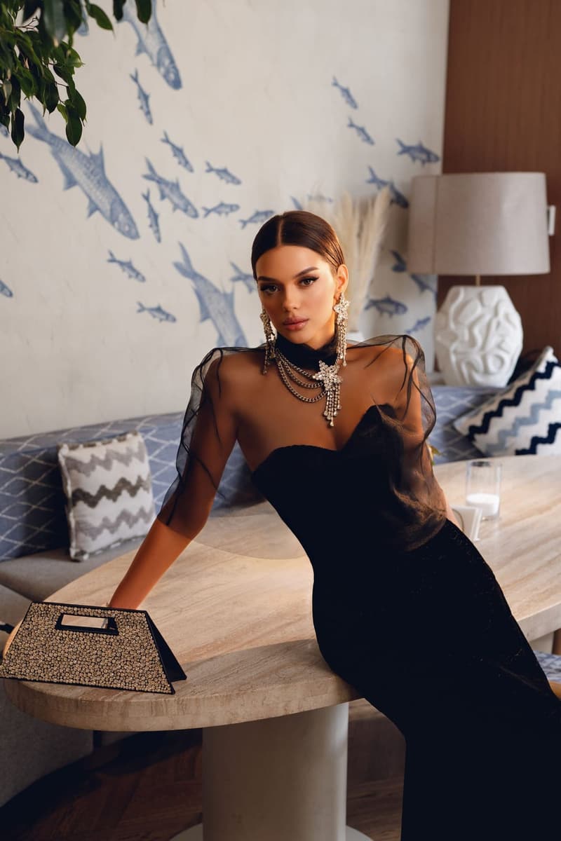 Woman in a black dress with sheer sleeves leaning on a table